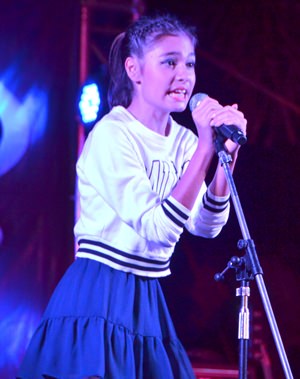 A budding, young singer demonstrates her vocal talents to the audience.