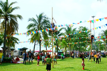 Children cheer the adults climbing the oily posts.