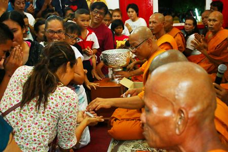 Citizens receive gifts from Phra Pladsuttassana Suthammo, abbot of Wat Bunyakanjanaram (middle).