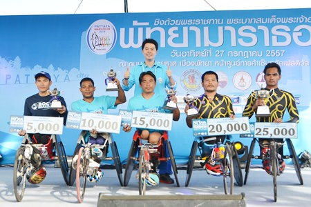 The top five in the wheelchair marathon pose on the podium with their trophies.  The race was won by Thailand’s Prawat Wahorom (far right).