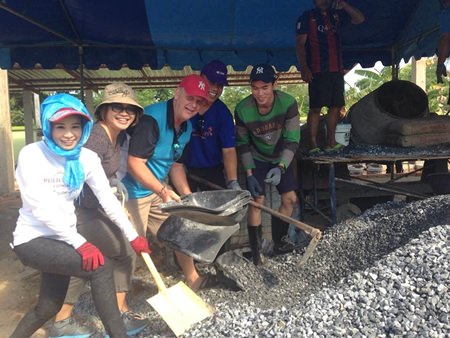 Praichit Jetpai (left), president of the YWCA Bangkok-Pattaya, and volunteers take part in mixing the concrete for the building.