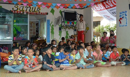 Children at the Sanuk Day Care Center sit and watch intently during the presentation of an afternoon of traditional Thai dance.