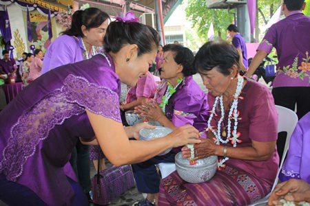 Members of the Woman’s Development Club pour scented water onto the hands of local elders on the occasion of Songkran.