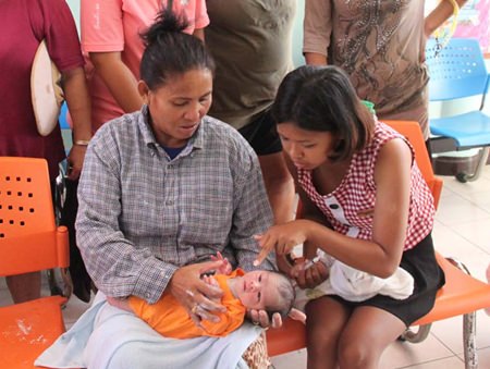 Motherly women crowd around the abandoned child. Wilai Tonelung (right) found the infant lying in a foam box at her family’s banana plantation in Sattahip.