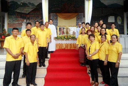 Members of the parish council stand in cordon in front of the pictures and relics of the two popes. In the background left is Rev. Peter Suraporn Suwichakorn.