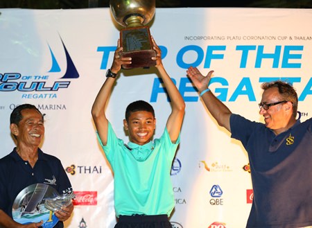 Suthon Yampinid lifts the 40-year old Thailand Optimist National Championship trophy, presented by Rear Admiral Sunan Monthardplin, Yacht Racing Association of Thailand and President of Junior Sailing Squadron (left), and past winner Mark Tchelistcheff (right).