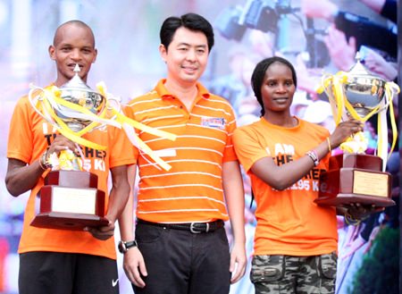 Pattaya Marathon 2015 winners, Onesmus Muasya (left) and Viola Jepchir Kimeli (right), both of Kenya, hold their HM King’s Cup trophies as they pose for photos with former MP Poramate Ngampichet.