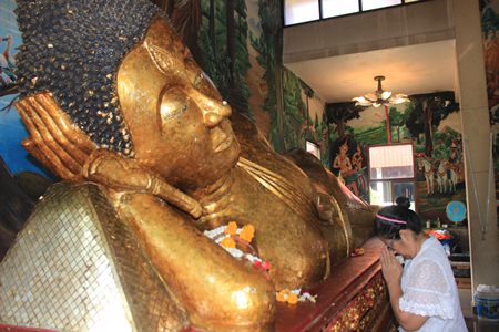 After adding her gold foil to the Buddha Statue at Luang Poh Tho, Wat Suttawas, she prays for the benefit of everyone in the world.