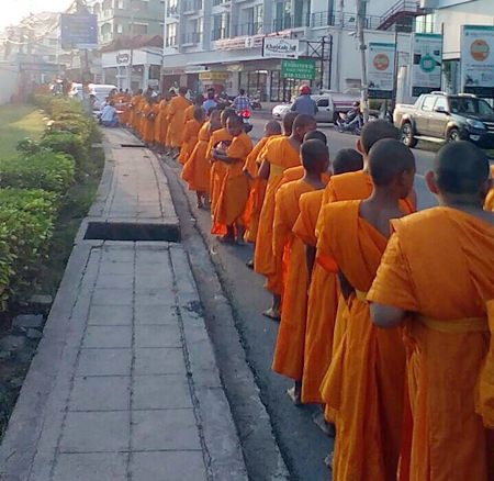 Young monks line the street to accept alms marking Auk Phansa, the end of Buddhist Lent.