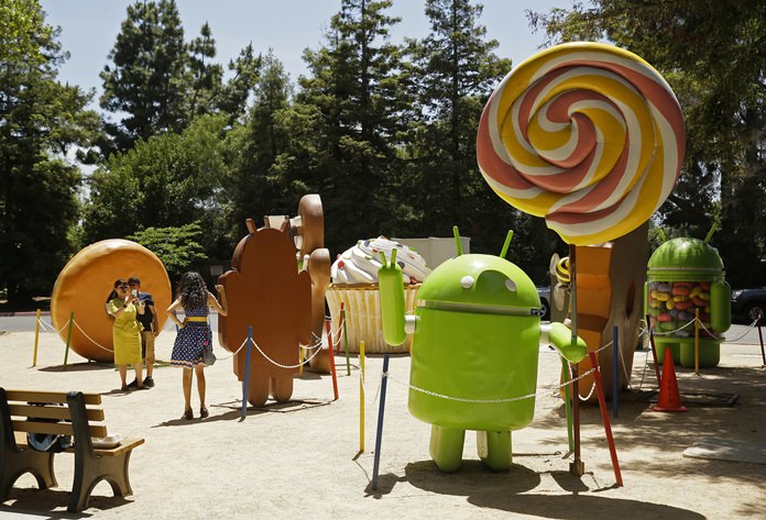 In this Wednesday, May 18, 2016, photo, people pose by Android lawn statues at Google’s headquarters in Mountain View, Calif. The tall sculpture, at right, depicts the 2014 version of Android, known as Lollipop. Although a newer version called Marshmallow has been available since October 2015, the bulk of Android phones still have Lollipop or older. Many phone makers and wireless carriers are slow to make the necessary tweaks and often don’t bother with older phones. (AP Photo/Eric Risberg)