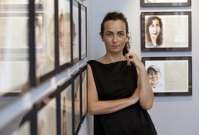 Aurelie Galois poses alongside her artwork at the French Cultural Center in Boston in this Tuesday, June 7, 2016 photo. (AP Photo/Michael Dwyer)