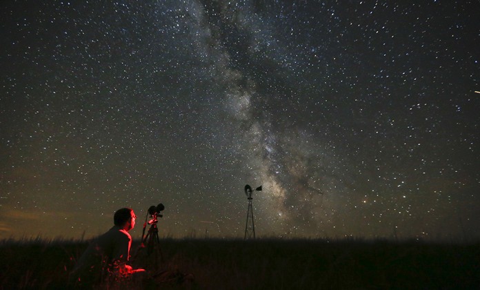 In this Wednesday, July 23, 2014 file photo, Omaha photographer Lane Hickenbottom photographs the night sky in a pasture near Callaway, Neb. With no moon in the sky, the Milky Way was visible to the naked eye. More than one-third of the world’s population can no longer see the Milky Way because of man-made lights, according to a scientific paper by Light Pollution Science and Technology Institute’s Fabio Falchi and his team members, published on Friday, June 10, 2016. (Travis Heying/The Wichita Eagle via AP)