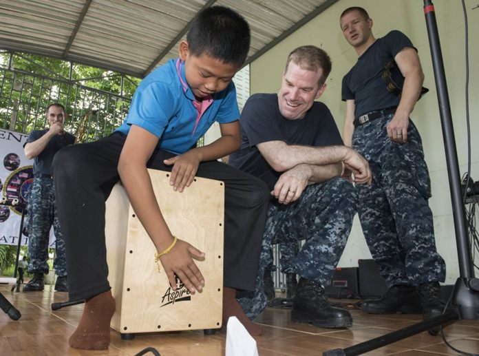Sattahip (June 22, 2016) The 7th Fleet Rock Band “Orient Express” teaches a student from Chuksamet School how to play a cajon box drum during a concert there. (U.S. Navy photo by Mass Communication Specialist 2nd Class Joshua Fulton/Released)