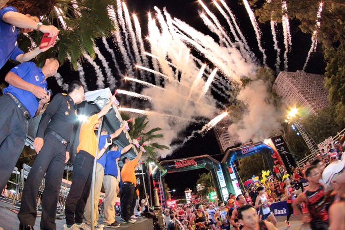 Fireworks explode across the sky as a multitude of runners, joggers and walkers cross the start line on Beach Road during the 2016 edition of the annual Pattaya City Marathon held in the early hours of Sunday morning, July 17. 