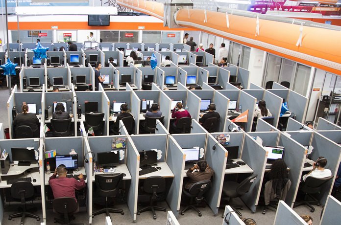 In this Aug. 13, 2014 file photo, workers sit at desks at a call center in the northern border city of Tijuana, Mexico. If you spend all day sitting, then you might want to schedule some time for a brisk walk - just make sure you can spare at least an hour. Not exercising and sitting all day is as dangerous as being obese or smoking, they found. (AP Photo/Alex Cossio, File)