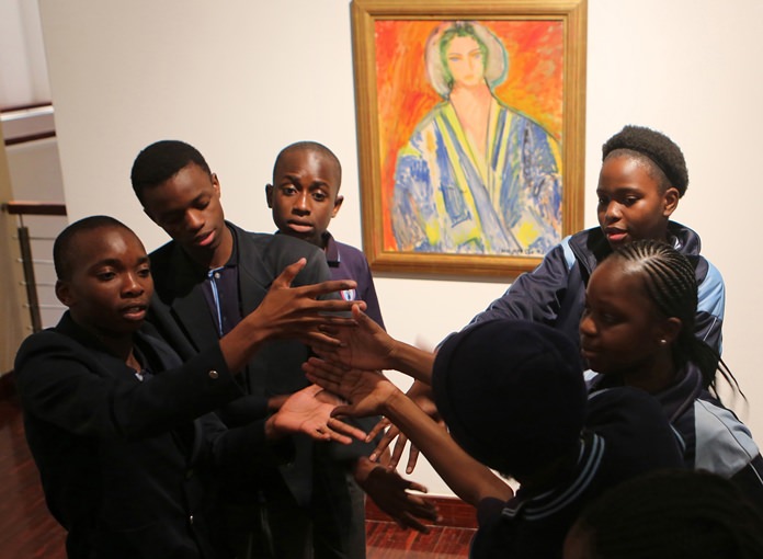 Students from the New Model School pose for a photo in front of a work by artist Henri Matisse in Johannesburg, South Africa. (AP Photo/Denis Farrell)
