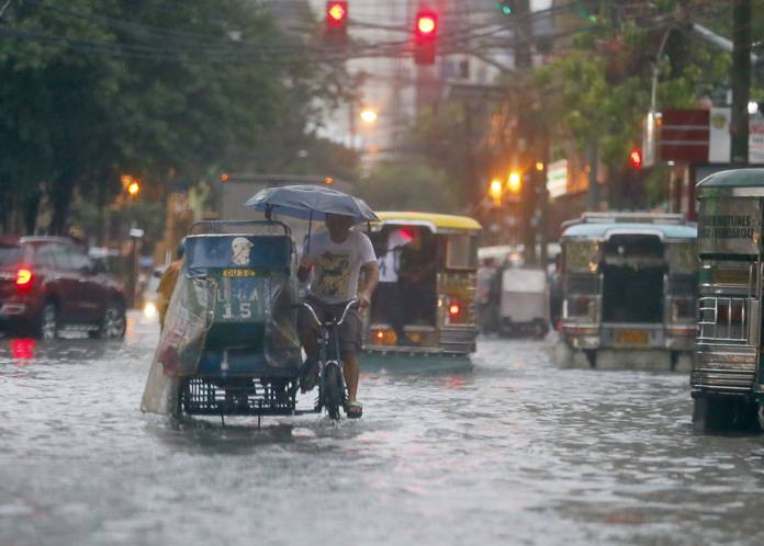 In this Aug. 26, 2016 file photo, commuters and motorists go on their way as heavy monsoon rains inundate low-lying areas in Manila, Philippines. Typhoons that slam into land in the northwestern Pacific - especially the biggest tropical cyclones of the bunch - have gotten considerably stronger since the 1970s, a new study concludes. (AP Photo/Bullit Marquez, File)