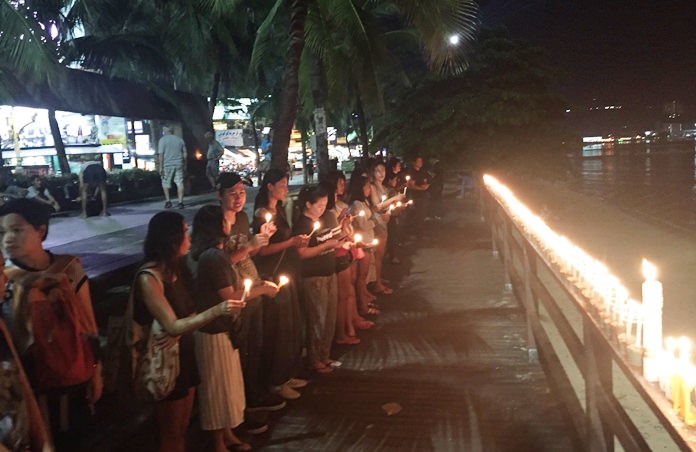 Residents join to light candles to guide HM the King to heaven at the Sailboat Monument.
