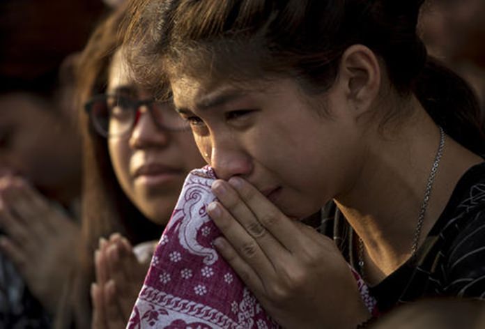 A Thai woman cries as she clasps hands with others to pay her last respects to a van carrying the body of the late King Bhumibol Adulyadej driving past outside Grand Palace in Bangkok. (AP Photo/Wason Wanichakorn)