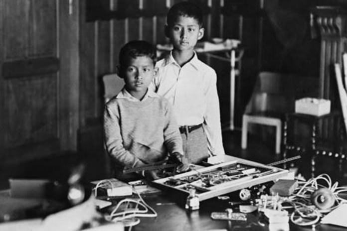 In this Sept. 22, 1935, file photo, ten-year-old King Ananda Mahidol of Siam, now known as Thailand, right, stands with his brother Prince Bhumibol, while playing with presents including a science kit he received on his tenth birthday, in Lausanne, Switzerland. (AP Photo, File)