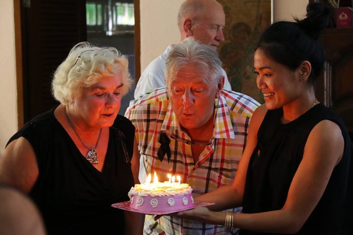 Witha Scholtes (left) and Joy Keolaphuomy help Aad Scholtes to blow out the candles on his birthday cake.
