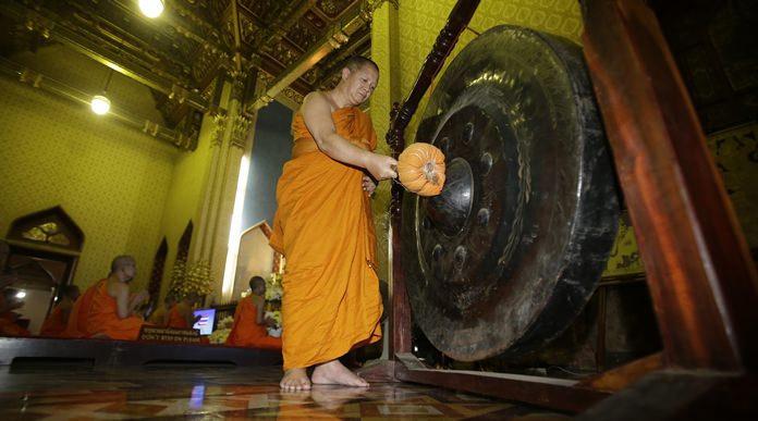 A Buddhist monk hits a gong as others pray in front of portrait HM King Maha Vajiralongkorn Bodindradebayavarangkun at the Marble temple in Bangkok, Thursday, Dec. 1, 2016. (AP Photo/Sakchai Lalit)