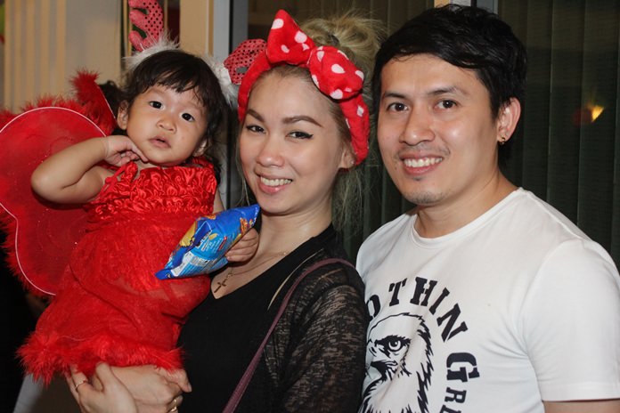 A handsome young couple and their child enjoy the Christmas spirit in church.
