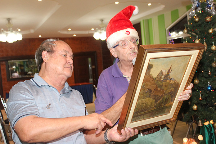 Martin Brands (right) explains details about the antique painting while Prem listens.