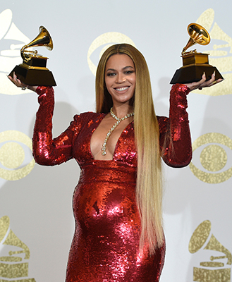 A pregnant Beyonce poses in the press room with the Grammy awards for best music video for "Formation" and best urban contemporary album for "Lemonade". (Photo by Chris Pizzello/Invision/AP)