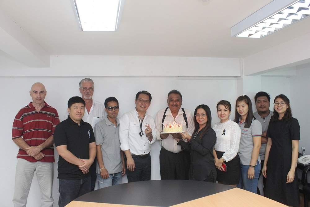 A small group of the Pattaya Mail family gather around to sing happy birthday to the chief.