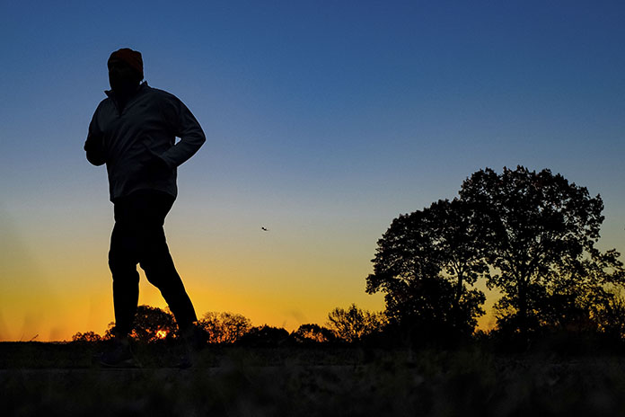A runner is silhouetted against the sunrise on his early morning workout near Arlington National Cemetery in Arlington, Va., across the Potomac River from the nation's capital. Research released on Monday, Jan. 9, 2017 suggests that people who pack their workouts into one or two days a week lower their risk of dying as much as those who exercise more often, as long as they get enough of it. (AP Photo/J. David Ake)