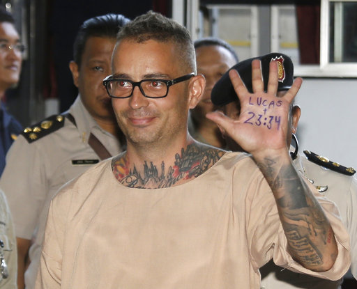 Artur Segarra Princep of Spain raises his hand displaying a popular Bible verse on the palm of his hand reading, "Lucas 23:34" as he arrives at the criminal court in Bangkok, Thailand, Friday, April 21, 2017.(AP Photo/Sakchai Lalit)