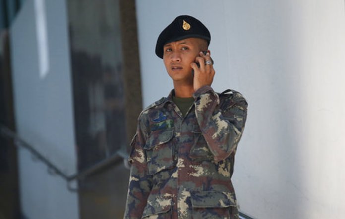 A Thai soldier talks on his cell phone in front of the entrance of Phramongkutklao Hospital.(AP Photo/Sakchai Lalit)