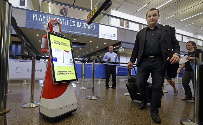 Airline passengers walk past a robot providing tips for getting through security faster during a pilot project as they head toward a security checkpoint Tuesday, July 11, 2017, at Seattle-Tacoma International Airport, in SeaTac, Wash. (AP Photo/Elaine Thompson)