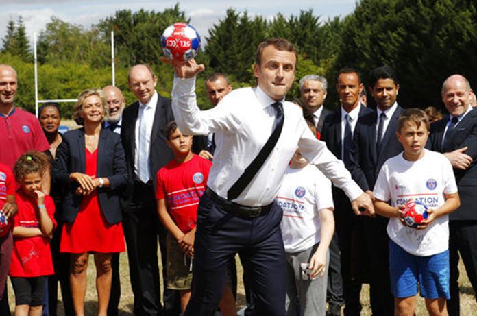 French President Emmanuel Macron throws a ball as he visits a recreation center in Moisson, east of Paris, France, Thursday, Aug. 3. (Philippe Wojazer/Pool Photo via AP)