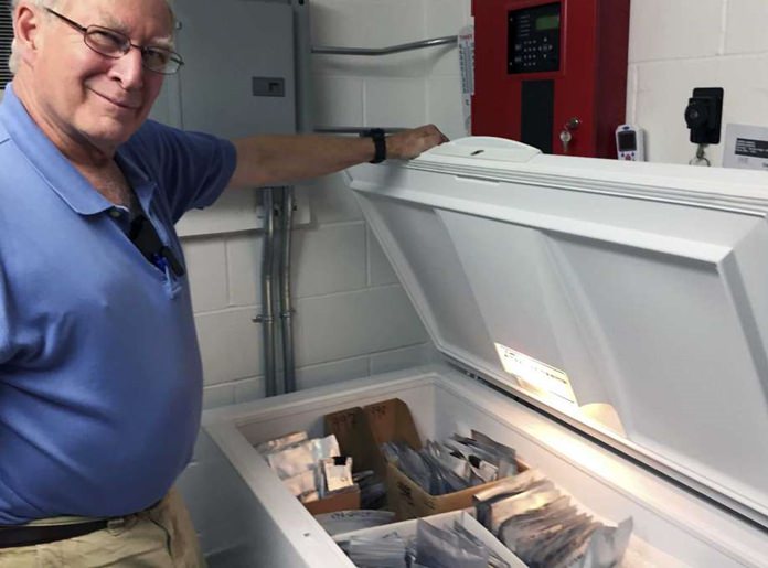 In this Aug. 31, 2017 photo, Bill Brumback, director of conservation at the New England Wild Flower Society, opens the “seed ark,” a freezer filled with seeds collected for safekeeping from rare and endangered plants in the region. (AP Photo/Bob Salsberg)