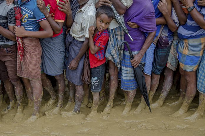 In this Tuesday, Sept. 19, 2017 file photo, a young Rohingya Muslim boy, who crossed over from Myanmar into Bangladesh, waits along with others for his turn to collect food aid near Kutupalong refugee camp, Bangladesh. With a mass exodus of Rohingya Muslims sparking accusations of ethnic cleansing from the United Nations and others, Myanmar leader Aung San Suu Kyi on Tuesday said her country does not fear international scrutiny and invited diplomats to see some areas for themselves. (AP Photo/Dar Yasin, File)