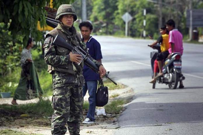A Thai soldier mans a checkpoint as members of the public look on near Pattani, southern Thailand. (AP Photo/David Longstreath)