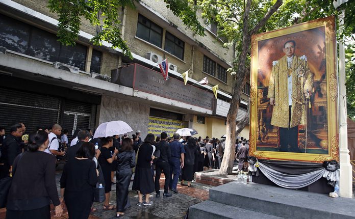 Mourners line up beside a of portrait of HM the late King Bhumibol Adulyadej to pay their respects to the Royal Urn outside the Grand Palace for last day of viewing in Bangkok, Thursday, Oct. 5, 2017. The royal cremation is scheduled on Oct. 26, 2017. Adulyadej died on Oct. 13 last year at age 88 after seven decades on the throne. (AP Photo/Sakchai Lalit)
