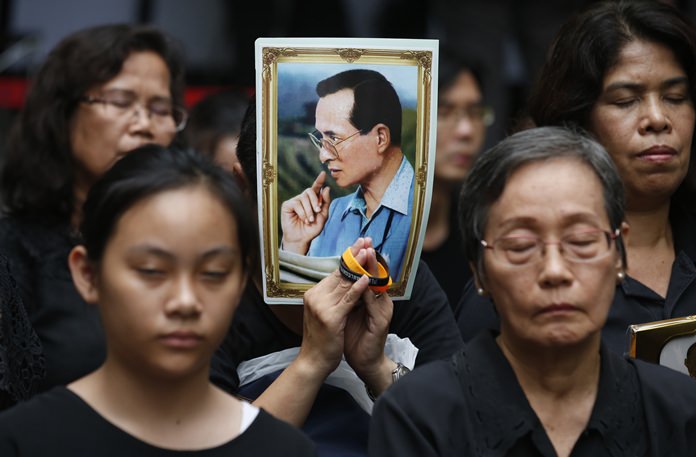 Mourners hold a portrait of His Majesty the late King Bhumibol Adulyadej during a moment of silence at Siriraj Hospital where he died a year earlier in Bangkok. (AP Photo/Sakchai Lalit)