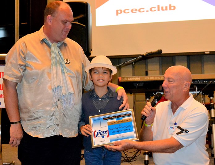 MC Roy Albiston presents Ben Rudolf with the PCEC’s Certificate of Appreciation for his musical presentation as Marcus Tristan looks on.