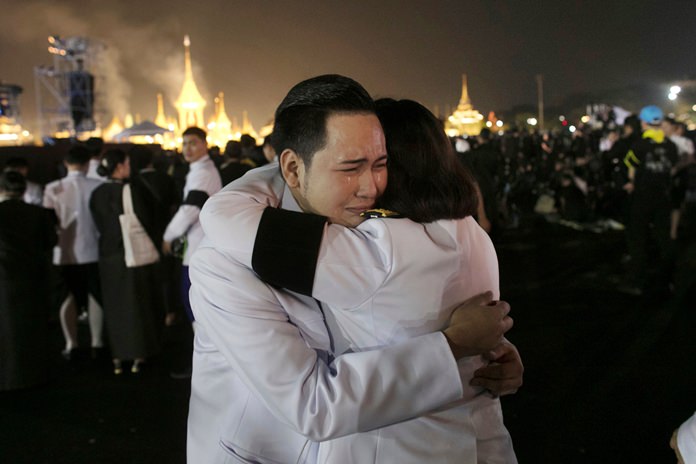Thai officials hug as smoke rises from the royal crematorium in Bangkok, early Friday, Oct. 27. (AP Photo/Wason Wanichakorn)