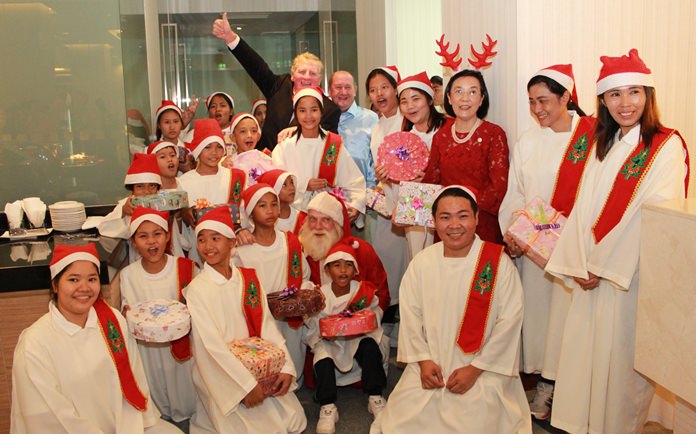 Maurice Roberts, president of the PSC waves as Khun Toy and Santa Claus pose for a group photo with the teachers and residents of the Pattaya Orphanage.