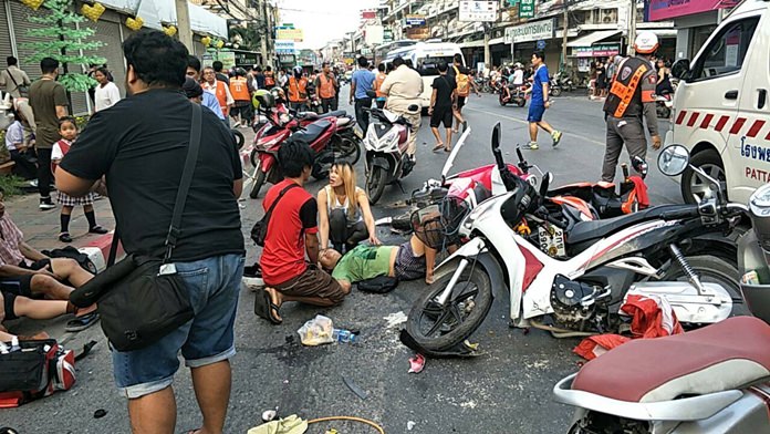 Motorbikes lie wrecked as passersby come to the aid of injured riders.