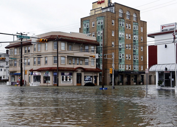 In this Oct. 30, 2012 file photo, the intersection of 8th Street and Atlantic Avenue is flooded in Ocean City, N.J., after the storm surge from Superstorm Sandy flooded much of the town. New satellite research shows that global warming is making seas rise at an ever increasing rate. (AP Photo/Mel Evans, File)
