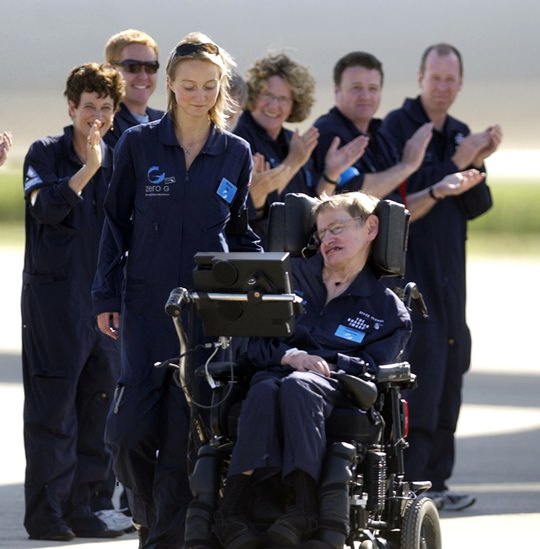 Astrophysicist Stephen Hawking is assisted off the tarmac at the Kennedy Space Center by his caregiver, Monica Guy, as he is applauded by members of the flight crew after completing a zero-gravity flight, Thursday, April 26, 2007. (AP Photo/Peter Cosgrove, File)