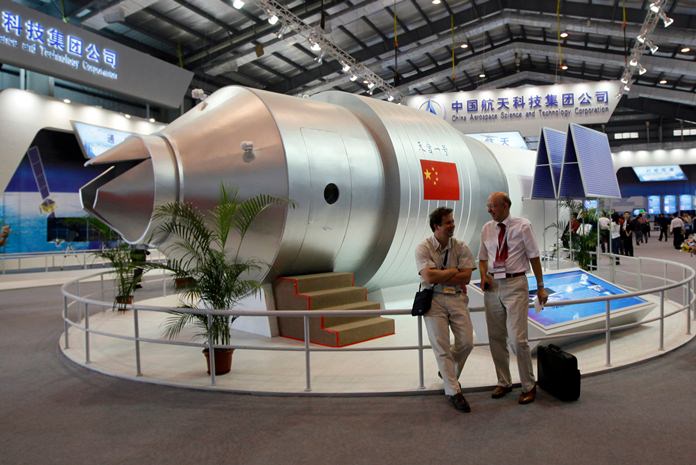 In this Nov. 16, 2010 file photo, visitors sit beside a model of China’s Tiangong-1 space station at the 8th China International Aviation and Aerospace Exhibition in Zhuhai in southern China’s Guangdong Province. (AP Photo/Kin Cheung, File)