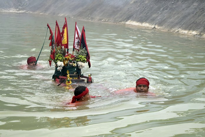 Devotees perform the ritual of bearing the image of Mae Lim Kor Niew through deep water.