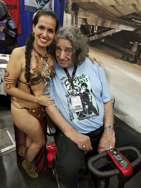 This May 29, 2018 photo shows Elisa Arguello (left) dressed in a Princess Leia costume posing with actor Peter Mayhew in Houston Texas as they launch the Chewbacca Challenge Coin, a fundraising campaign for underprivileged children in Venezuela. (Elisa Arguello via AP)