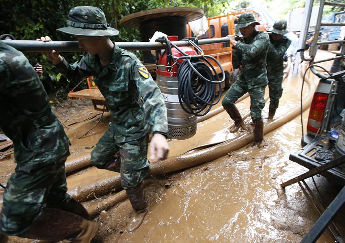 Soldiers carry a pump to help drain the rising flood water in a cave where 12 boys and their soccer coach have been missing in Mae Sai, Chiang Rai province, northern Thailand, Friday, June 29, 2018. (AP Photo/Sakchai Lalit)